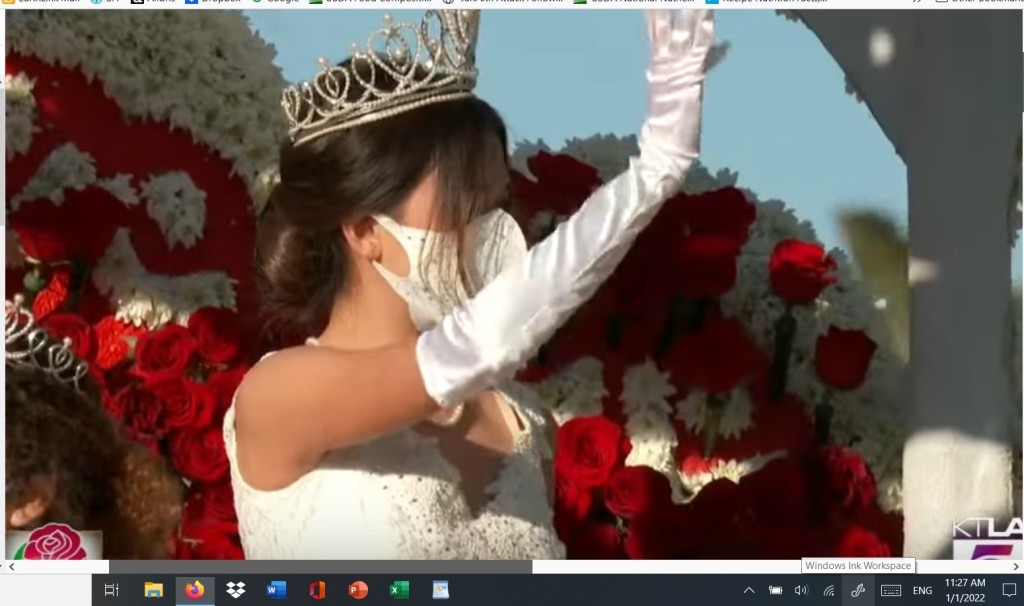 RoseParade2022-RoseQueen is wearing a facemask as she waves to the crowd.